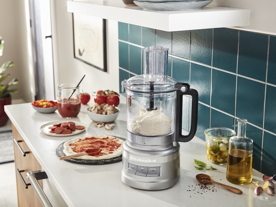 KitchenAid KFP0921CU Contour Silver 9-cup processor with dough in the work bowl and pizza ingredients nearby